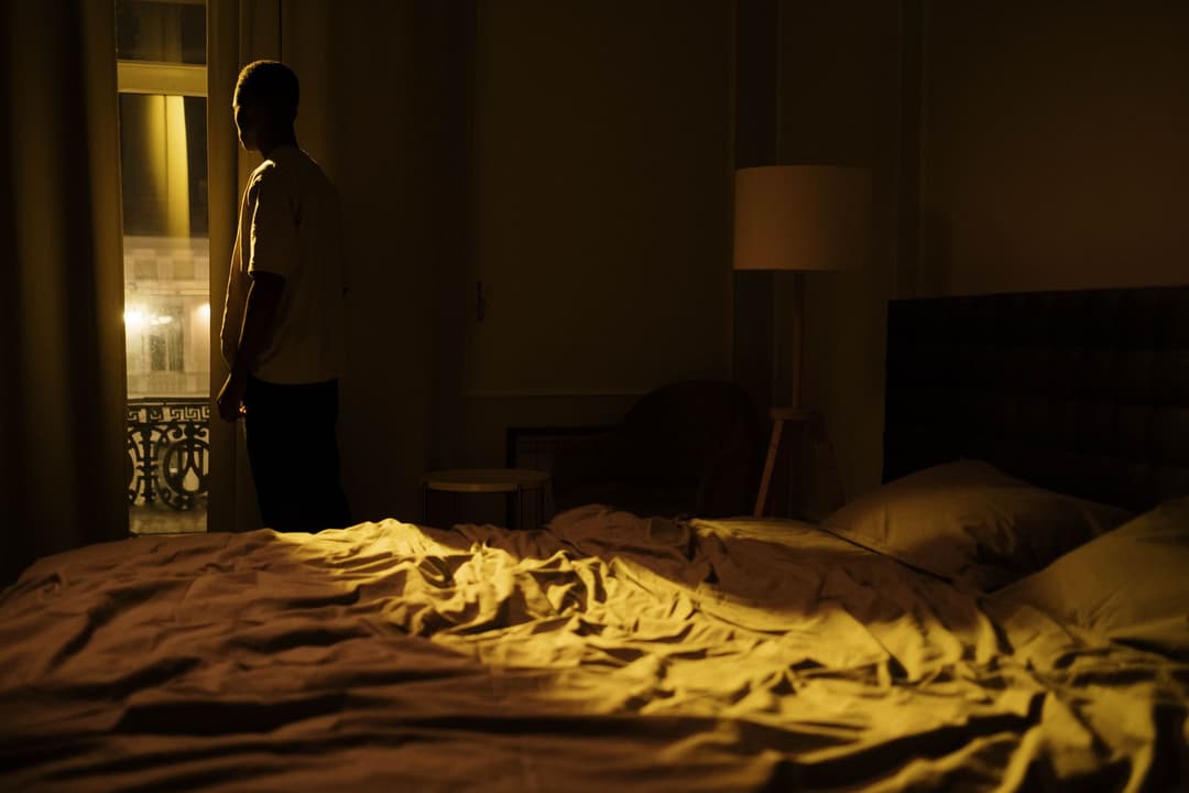 Man sitting in a dark bedroom at night, awake