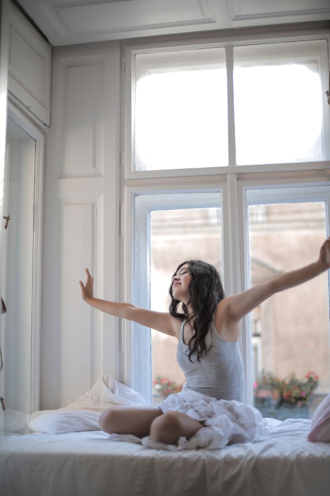 Woman stretching in bed in morning sunlight