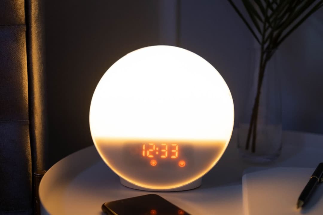Glowing bedside clock showing 12:33 in a dark bedroom