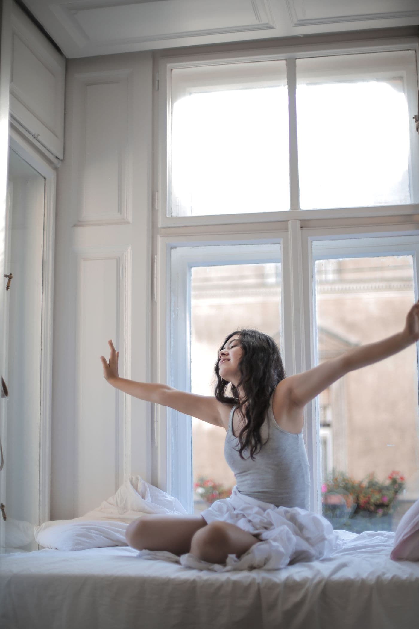 Woman stretching in bed in morning sunlight
