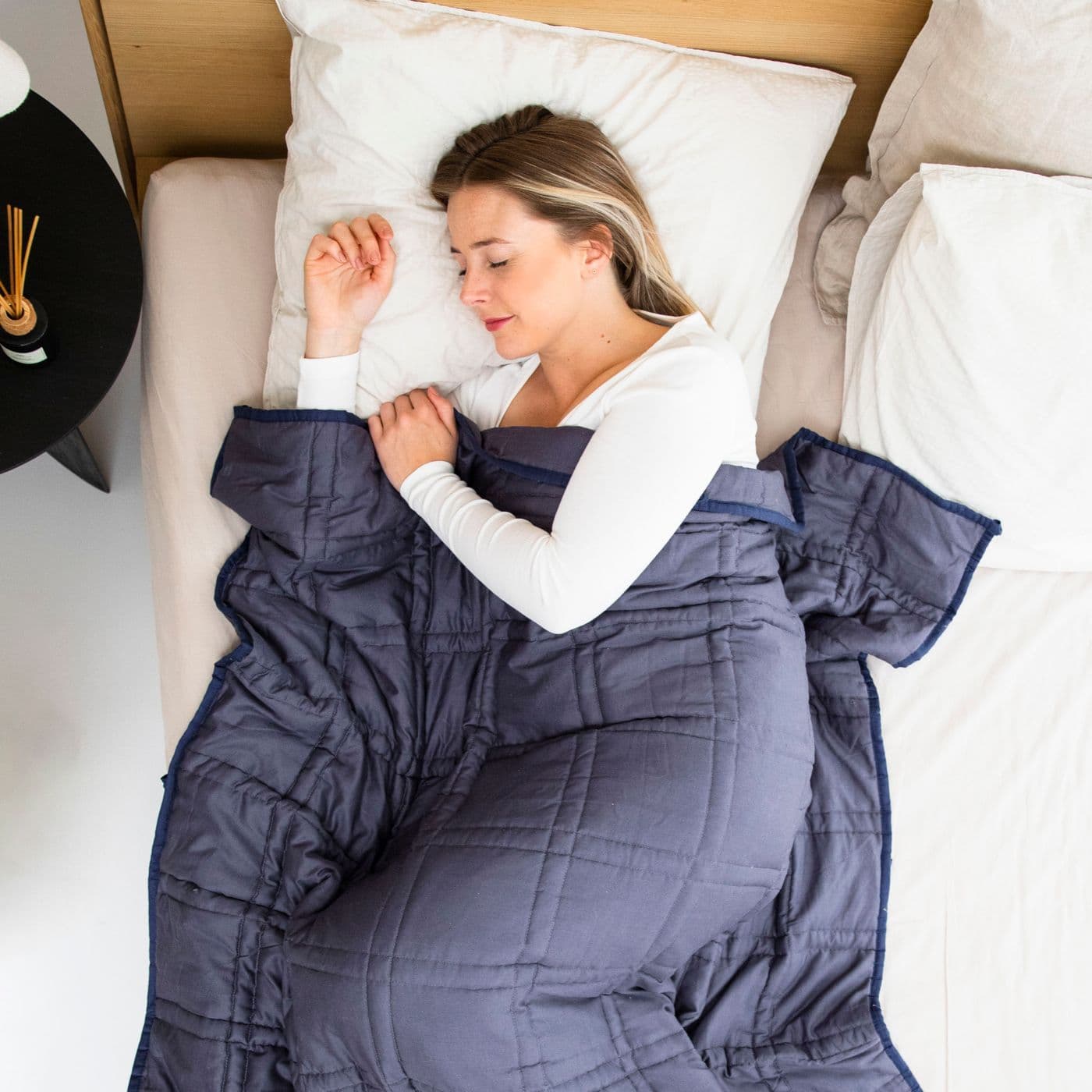 Woman sleeping under a navy weighted blanket