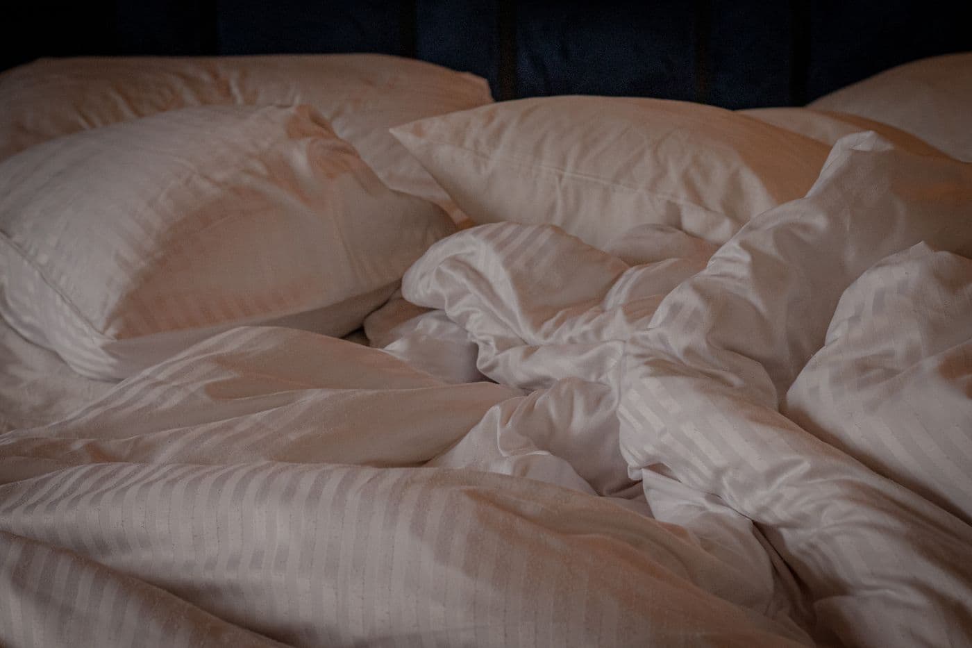Comfortable bed with white pillows and a crumpled duvet