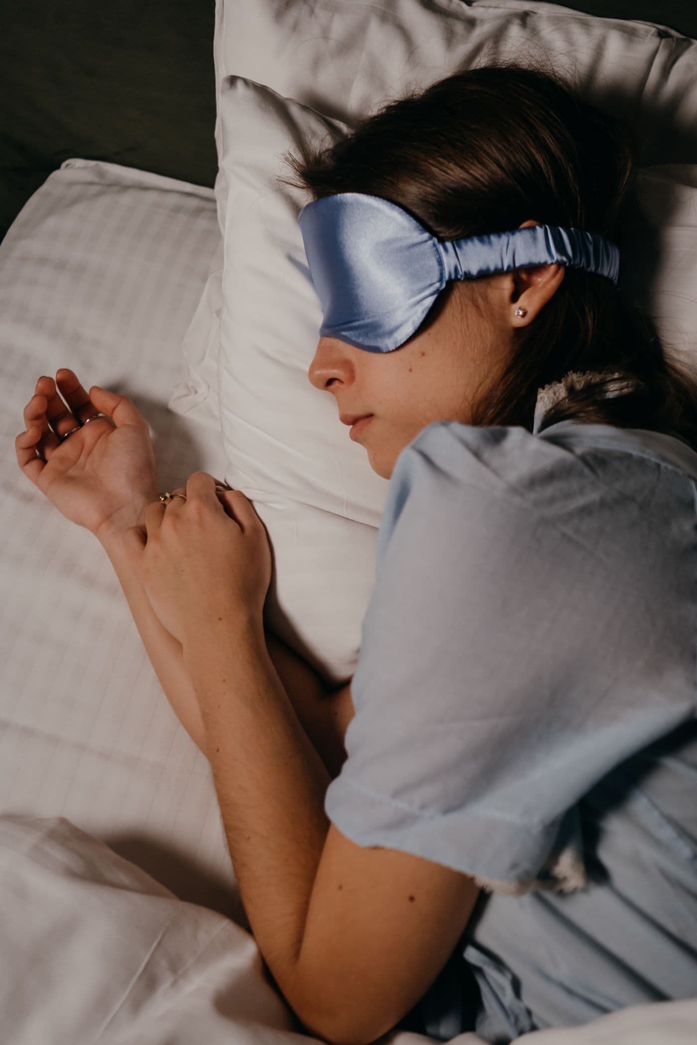 Woman wearing a blue eye mask resting in bed