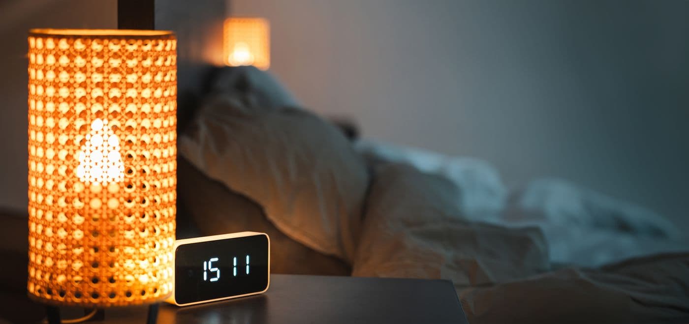 Warm bedroom with a glowing lamp and digital clock